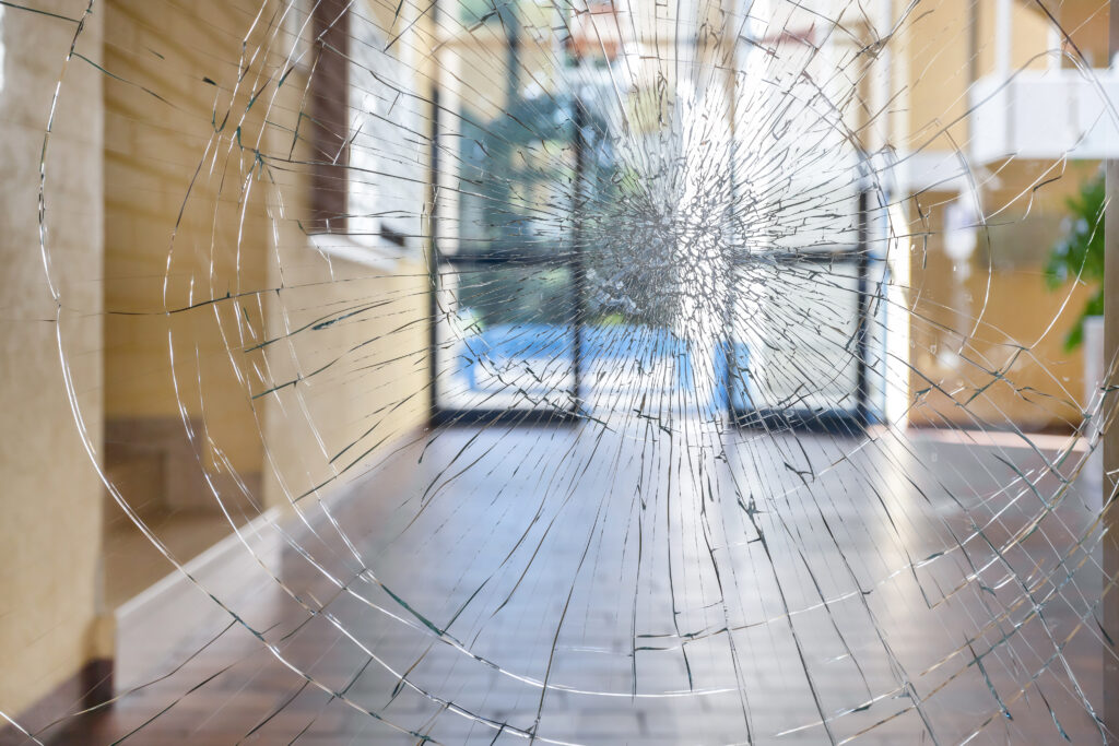 Shattered glass pane with cracks spreading out from a central impact point